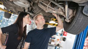 A mechanic from The Bridge Auto shows a customer what's wrong with her car.