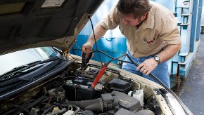 A mechanic from The Bridge Auto Philadelphia works on the battery for a car.